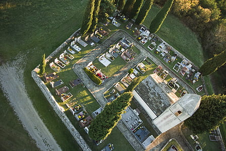 aerial view of church beside graveyard with trees thumbnail