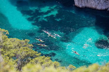 people boating at body of water near mountain thumbnail
