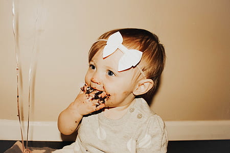 photo of baby with dessert food on her hand trough her mouth thumbnail