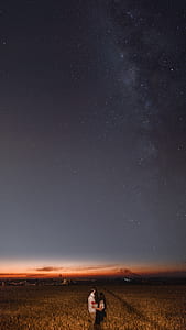 couple standing on field under starry skies thumbnail