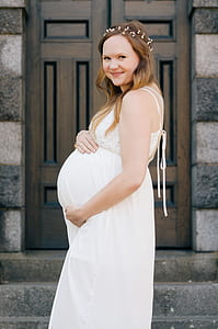 pregnant woman smiling while touching baby bumps at daytime thumbnail