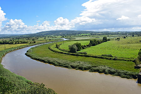river and green grass field during daytime thumbnail