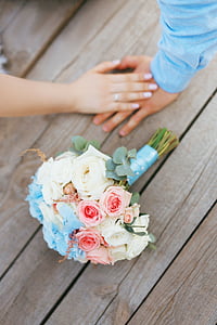 white, pink, and blue roses bouquet near couple holding hands thumbnail