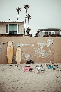 two brown wooden surfboards on brown concrete wall thumbnail
