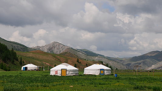 several round white tents on green field overlooking mountains at daytime thumbnail