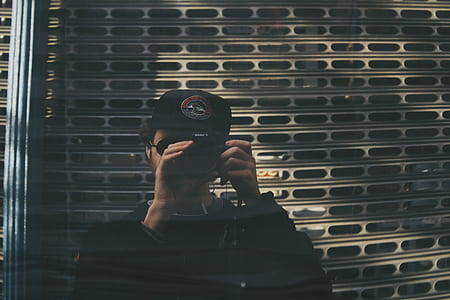 man taking photo near white metal wall thumbnail