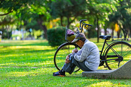 man sitting beside commuter bicycle near trees thumbnail