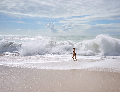 woman standing on seashore during daytime thumbnail