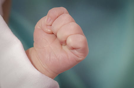 selective focus photography of infants hand forming a fist thumbnail