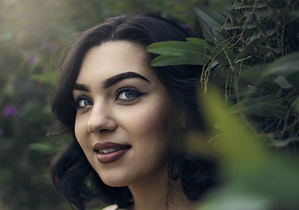 smiling woman wearing red lipstick near green leaf plant thumbnail