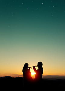 silhouette of man and woman drinking wine glasses during sunset thumbnail