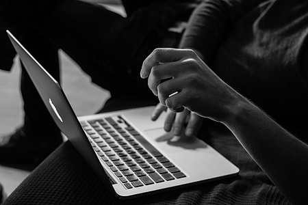 silver MacBook on person's legs thumbnail