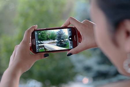 woman taking picture using red Samsung Android smartphone thumbnail