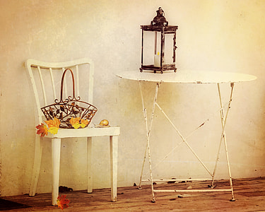 person taking photo of brown candle sconce on white metal folding table near white chair with brown wrought iron basket on top thumbnail