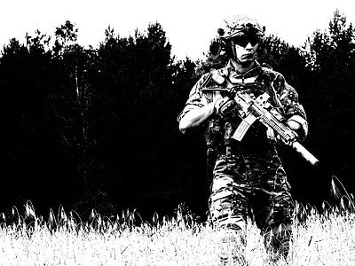 man walking on grass while holding rifle thumbnail