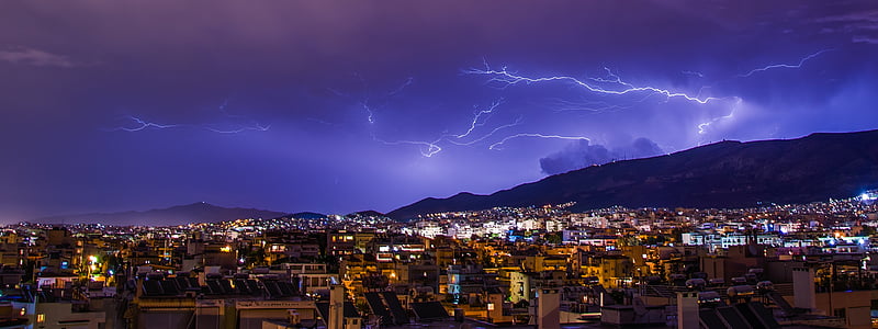 lightning occurring above mountain near city thumbnail