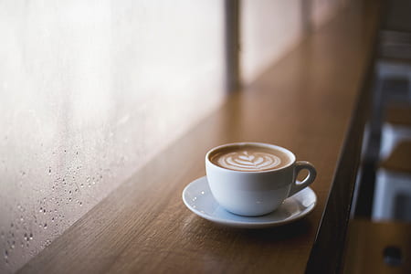 white ceramic teacup filled with coffee on white round ceramic saucer thumbnail