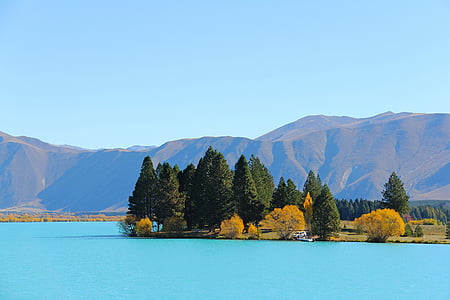 blue body of water beside trees and mountain thumbnail