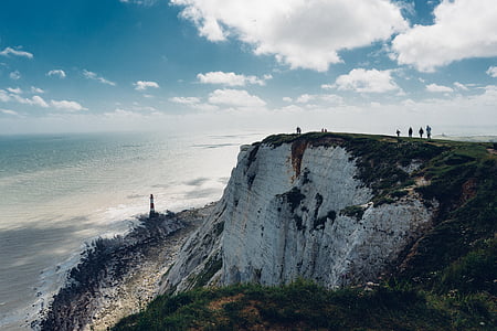 people standing near cliff under blue sky thumbnail