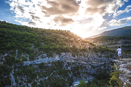 man standing on mountain during white and gray cloudy sky thumbnail