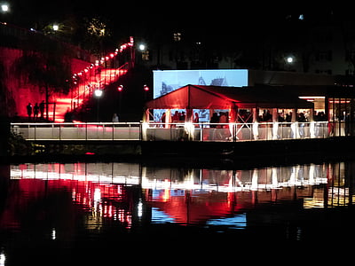 group of people gathering beside body of water during night time thumbnail