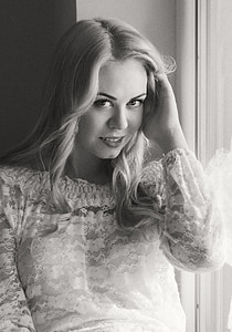 grayscale photo of woman standing beside window thumbnail