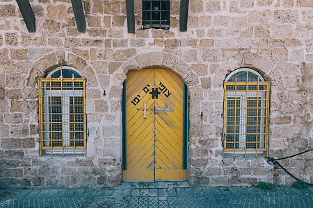yellow and green wooden closed door on brown brick wall thumbnail