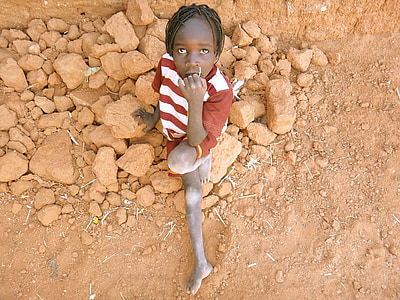 boy sitting on brown rock at daytime thumbnail