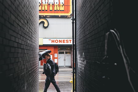 man walking while holding umbrella thumbnail