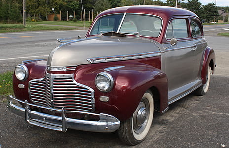 classic red coupe at the road during daytime thumbnail