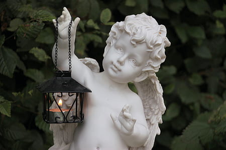 black lantern lamp hanging on white ceramic cherub angel figurine thumbnail
