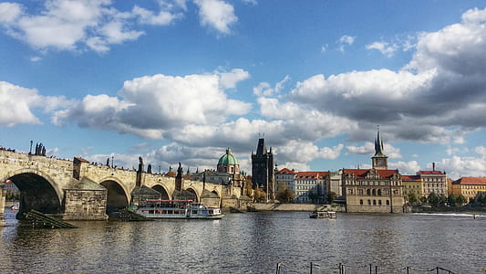 building across body of water under white clouds and blue sky thumbnail