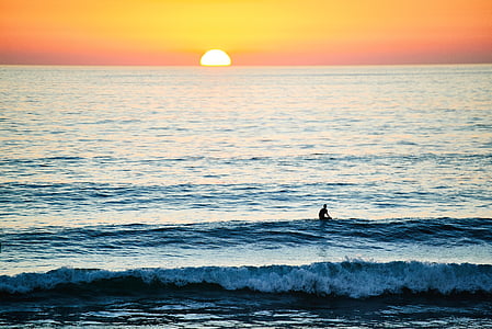 person in body of water during golden hour thumbnail