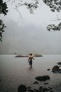 man stand on lake in a distance of a mountain thumbnail