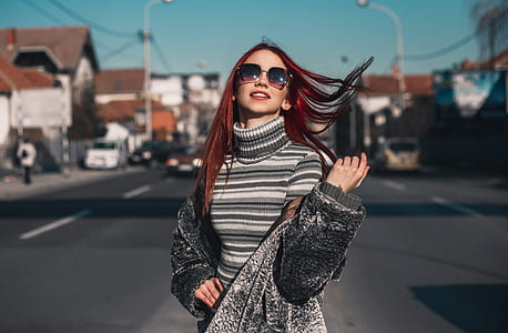 close-up photo of woman white and gray striped knitted turtleneck blouse and gray suede coat standing on black asphalt road during daytime thumbnail