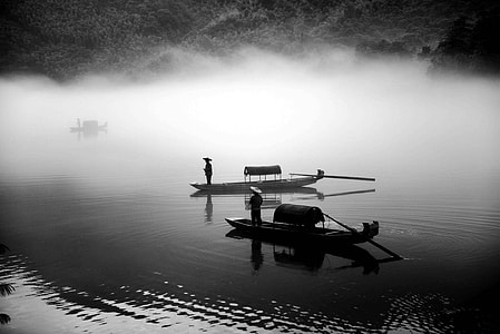 two man in boats on body of water grayscale photography thumbnail