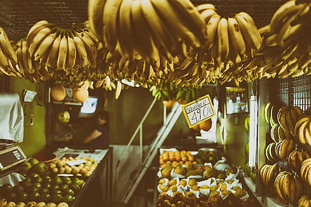 yellow banana hanging above other fruits thumbnail