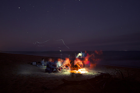 group of people lit fire near shoreline thumbnail