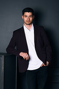 man wearing black blazer standing in front of black painted wall thumbnail
