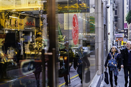 Man and Woman Passing Through Building With Glass Facade thumbnail