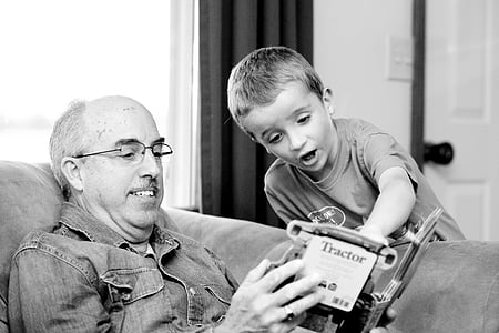 man sitting on chair opening book in front of boy thumbnail
