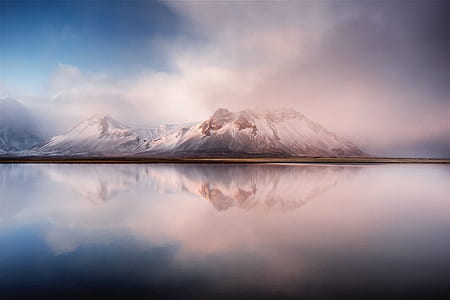 snow-covered mountain near body of water surrounded with fogs thumbnail