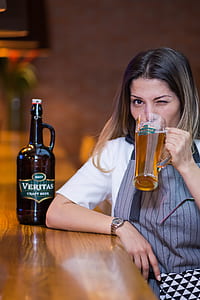 woman drinking beer beside brown wooden desk thumbnail