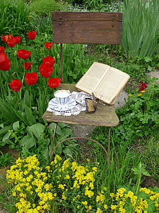 brown printed book beside case and teacup with saucer plate on chair thumbnail