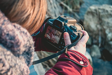 black woman holding black Canon DSLR camera thumbnail