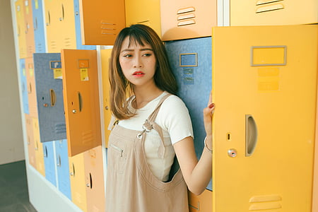 woman in white crew-neck T-shirt leaning on lockers thumbnail