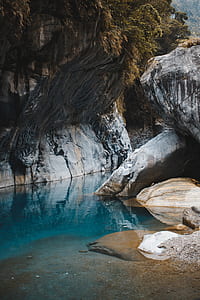 body of water between rock formation at daytime thumbnail