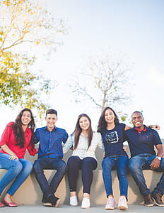 five people sitting on white bench thumbnail