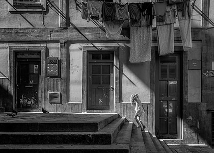 gray scale photo of girl on stairs under assorted hanged clothes thumbnail