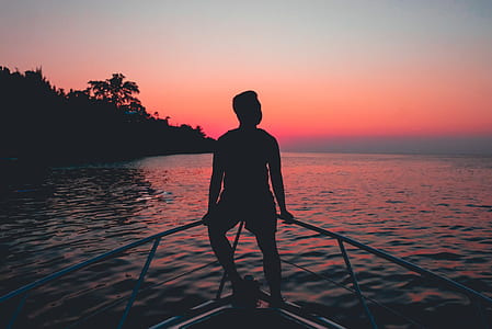 man sitting on bar near body of water thumbnail